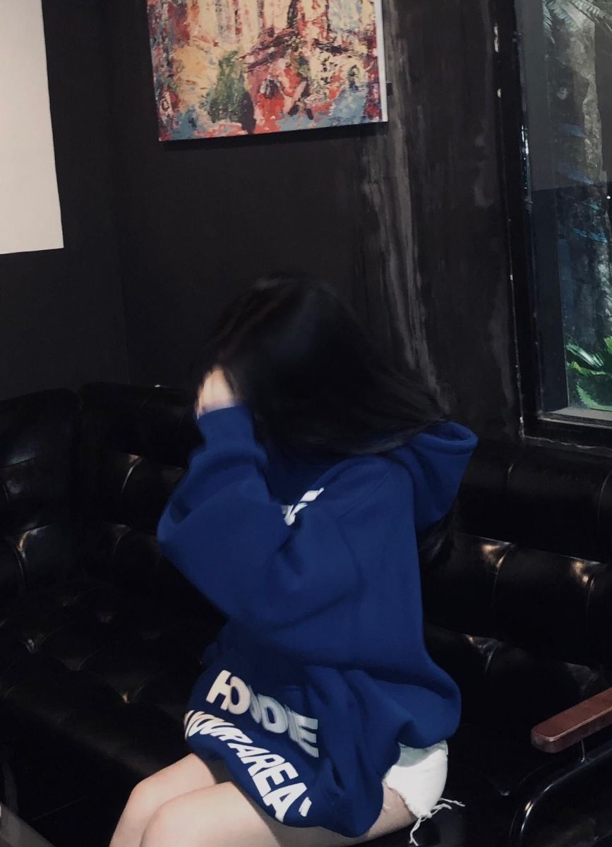 Ảnh gái trẻ mặc hoodie xanh dương ngồi trên ghế sofa