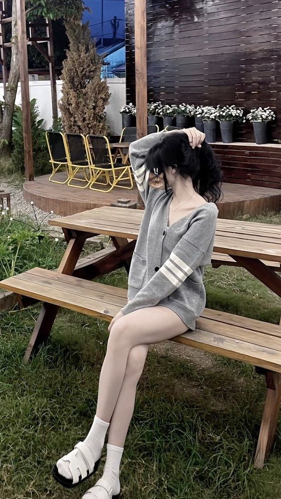 Cô gái che mặt xinh đẹp trong cardigan xám tại quán cà phê ngoài trời