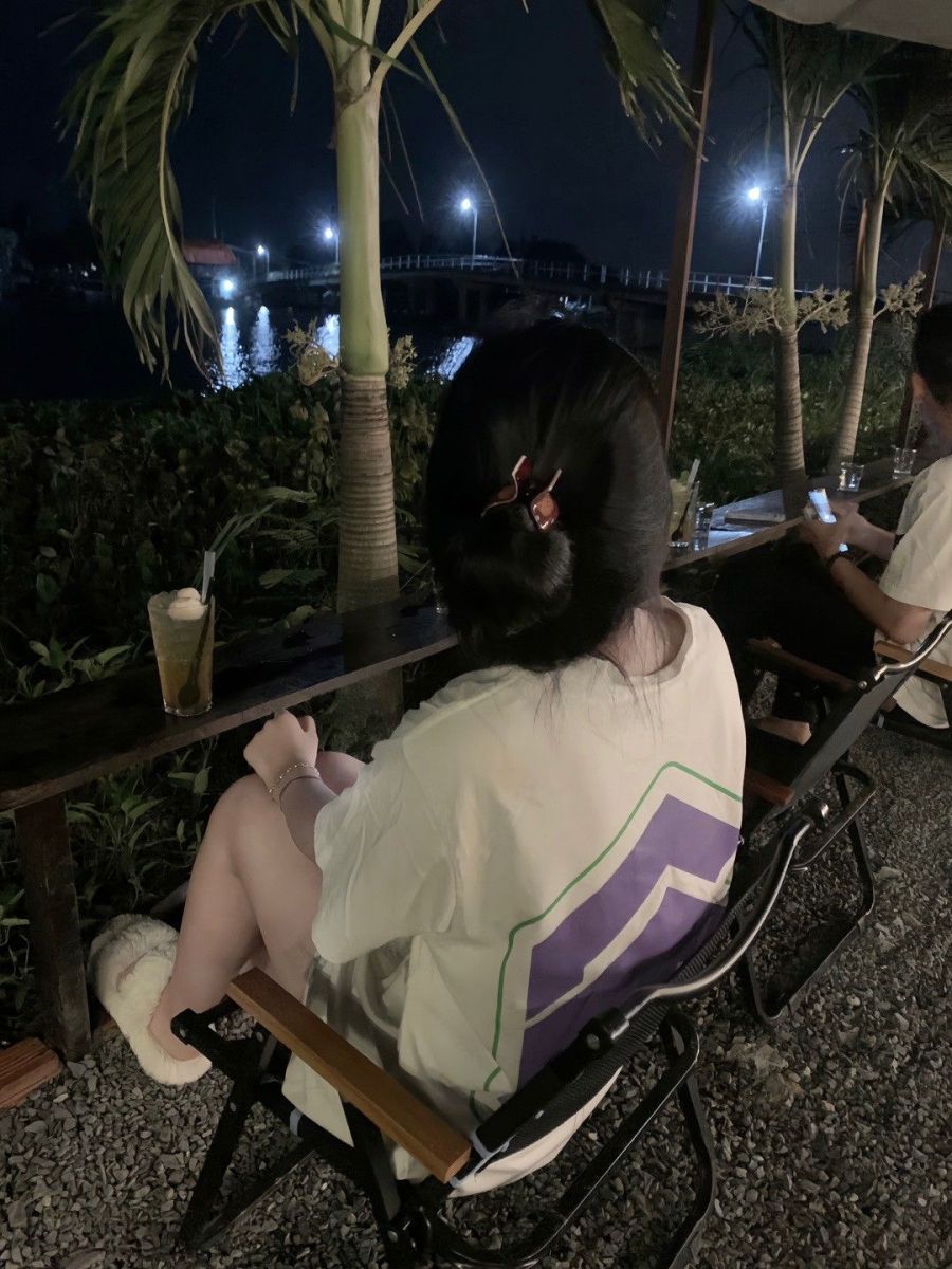 Cô gái đẹp trong áo phông rộng trên ghế gỗ ngoài trời