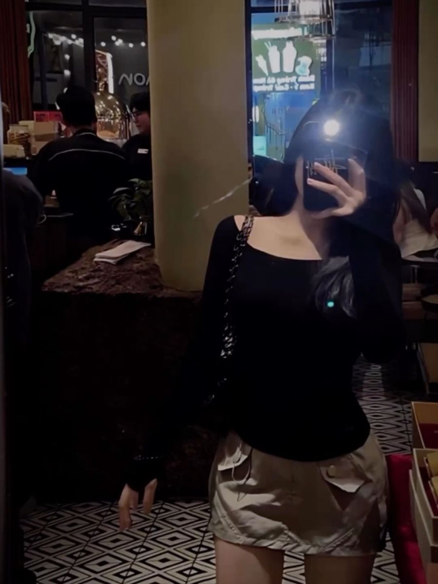 Cô gái mặc áo dài tây đen chụp ảnh selfie trong quán cà phê hiện đại