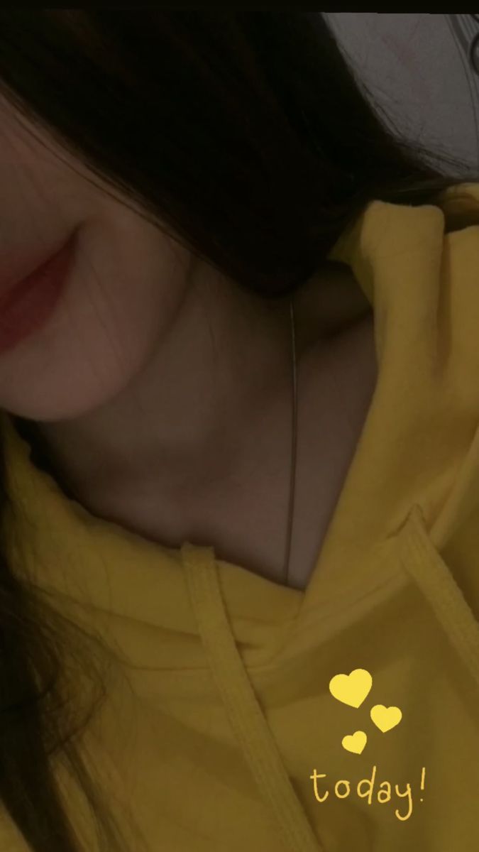 Cô gái mặc áo hoodie màu vàng chụp ảnh selfie trong không gian tối giản