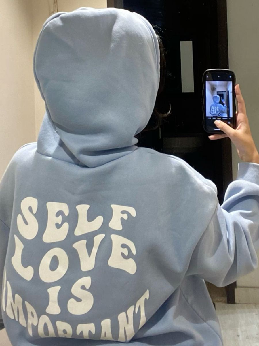 Cô gái mặc áo hoodie xanh nhạt chụp selfie với điện thoại