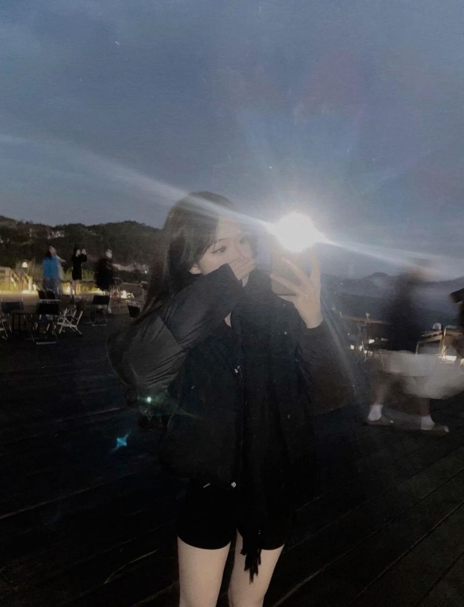 Cô gái mặc áo khoác đen chụp ảnh selfie buổi tối