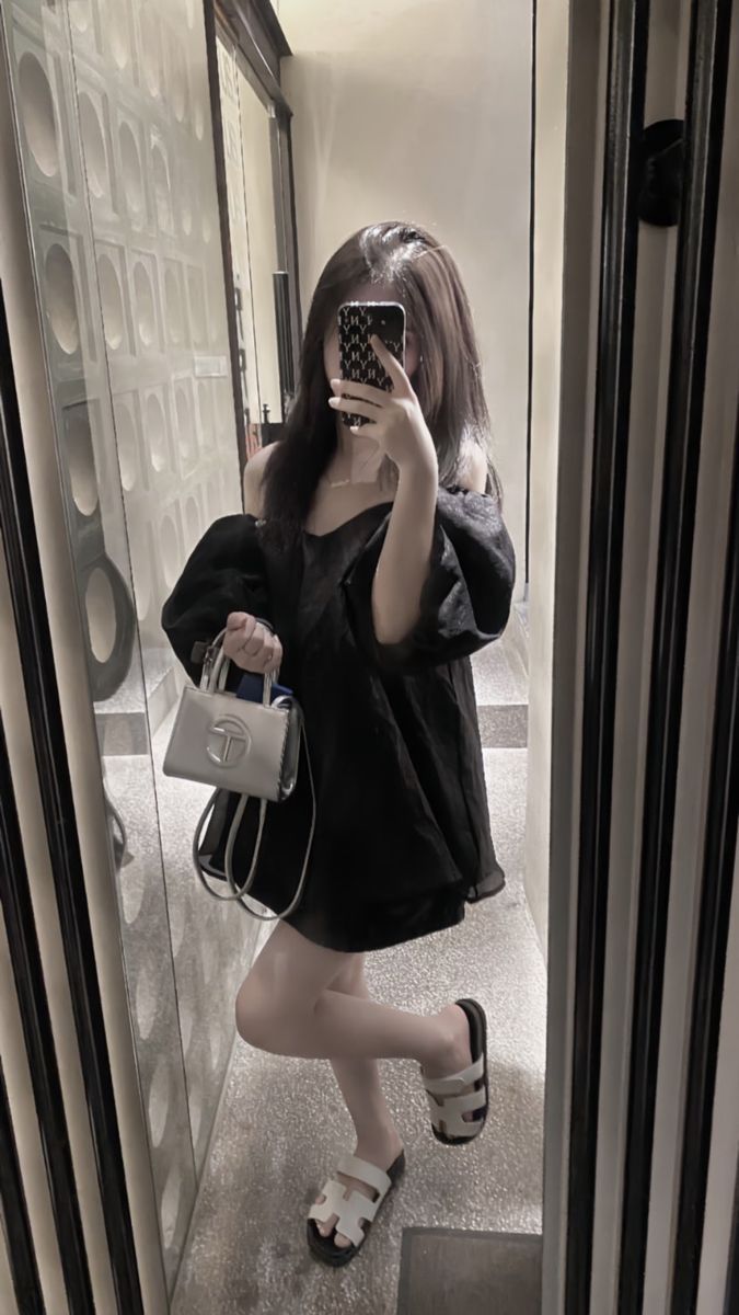 Cô gái mặc áo phông đen, diện sandal trắng trước gương