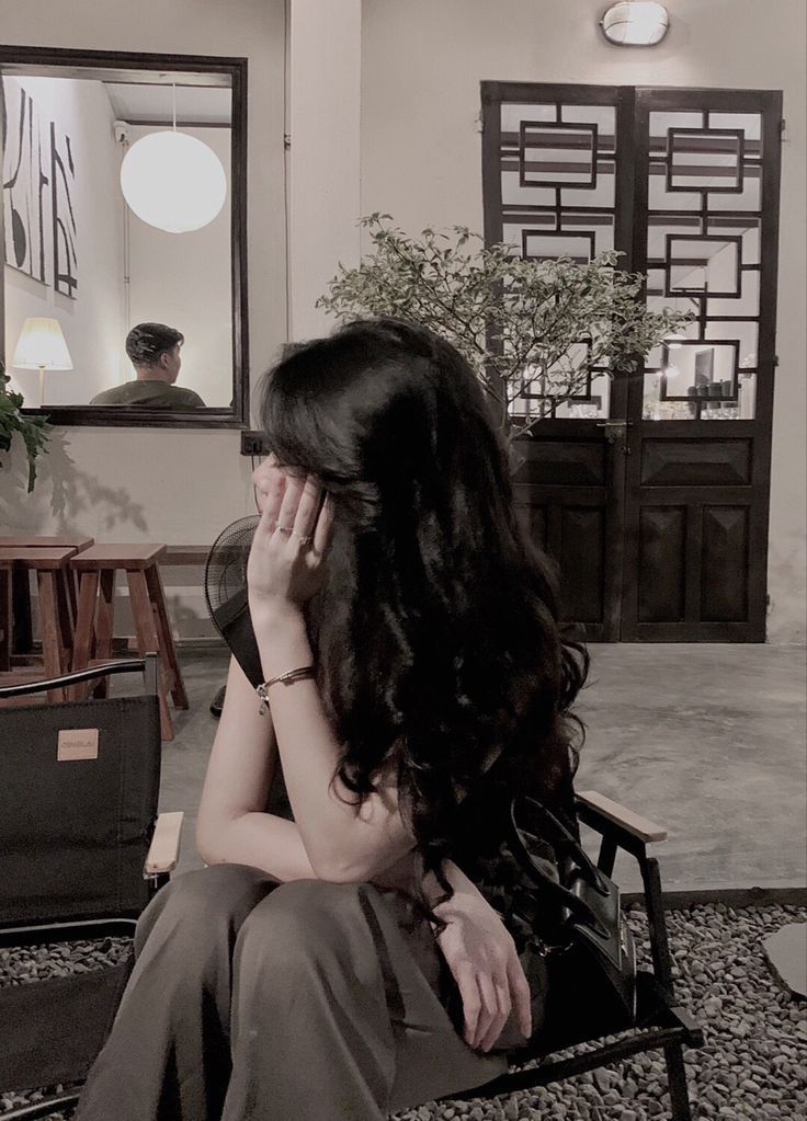 Cô gái ngồi trên ghế với trang phục đơn giản, tạo cảm giác suy tư