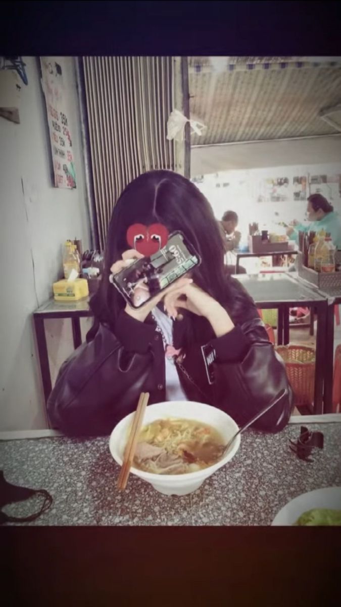 Cô gái trẻ che mặt trong quán ăn với áo khoác đen