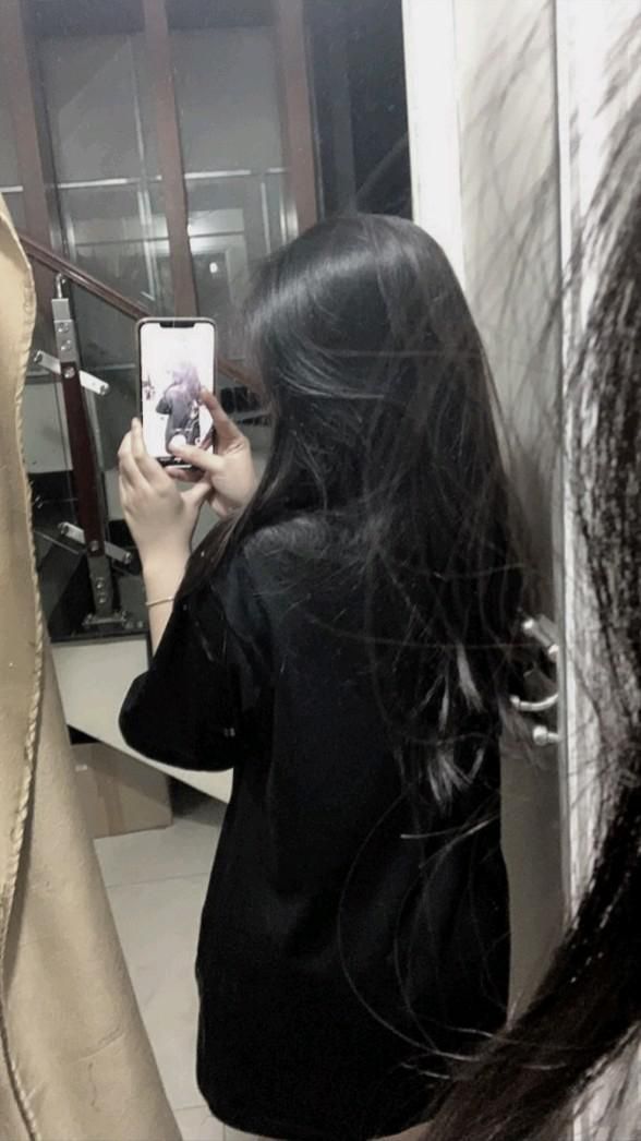Cô gái trẻ chụp ảnh selfie trong gương với áo phông đen