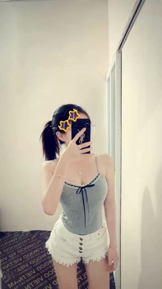Cô gái trẻ mặc áo ba lô xám và quần short trắng chụp ảnh selfie