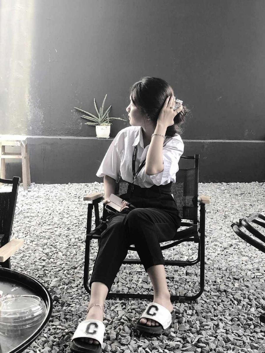 Cô gái trẻ mặc áo blouse trắng và quần đen ngồi thư giãn