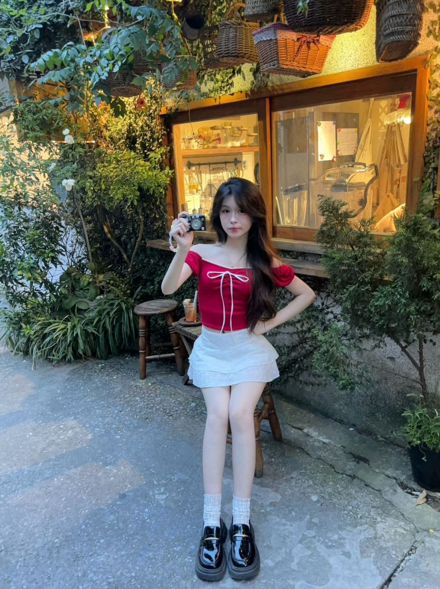 Cô gái trẻ mặc áo crop top đỏ và chân váy trắng chụp ảnh