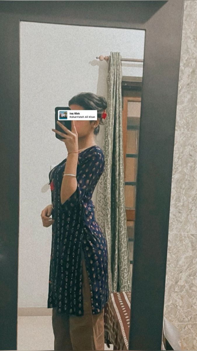 Cô gái trẻ mặc áo dài màu xanh bên gương lớn
