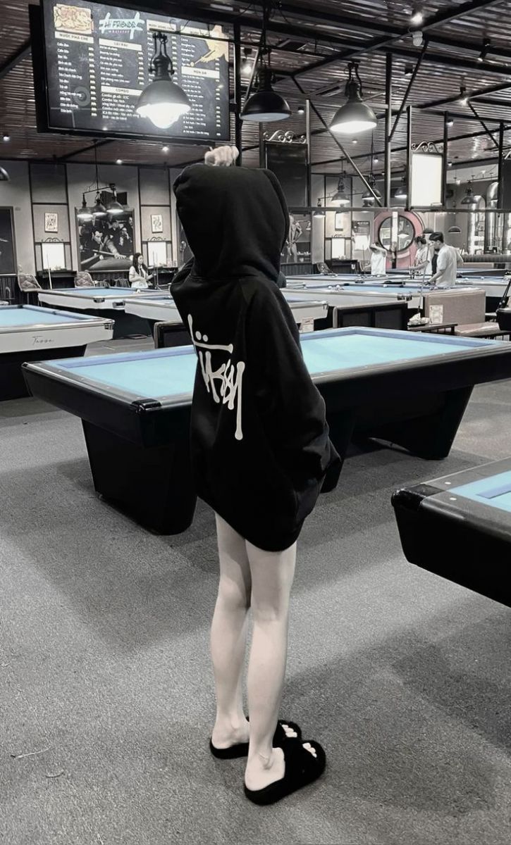 Cô gái trẻ mặc áo hoodie đen tại quán cà phê