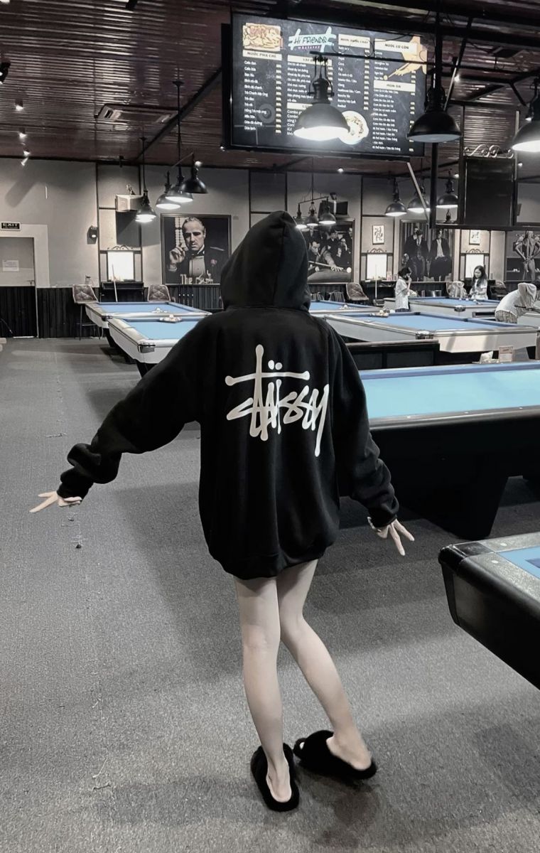 Cô gái trẻ mặc áo hoodie đen với logo trắng