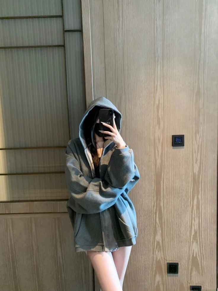 Cô gái trẻ mặc áo hoodie xám tạo dáng chụp ảnh selfie