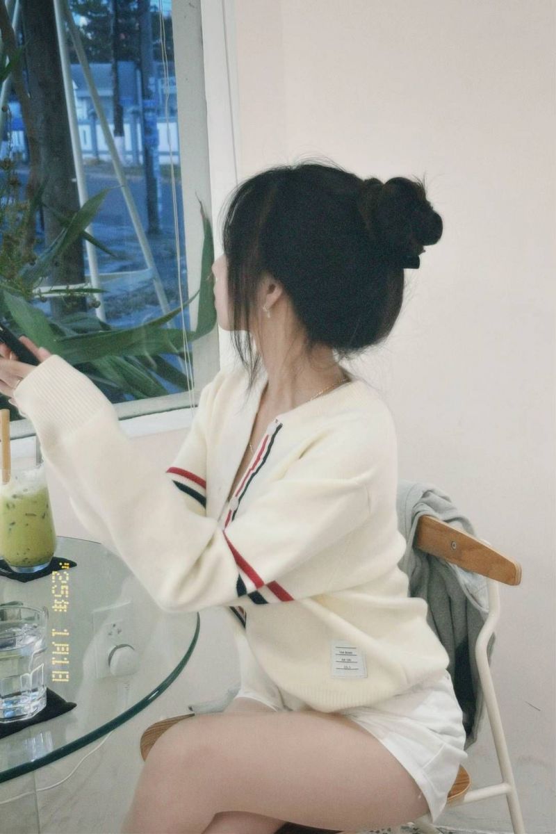 Cô gái trẻ mặc áo len trắng, quần ngắn xinh đẹp tại quán cà phê