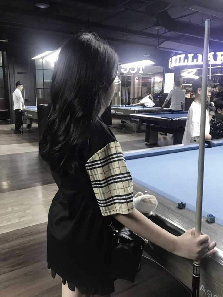 Cô gái trẻ mặc áo phông đen bên bàn bi-a