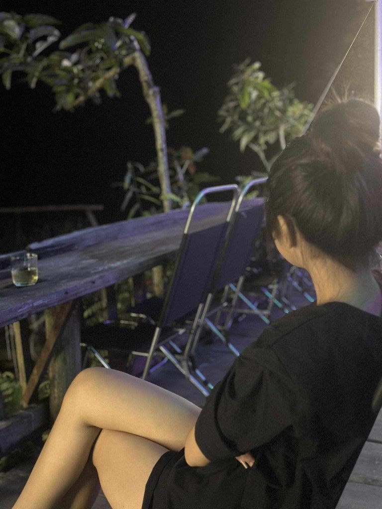 Cô gái trẻ mặc áo phông đen ngồi dưới ánh nắng