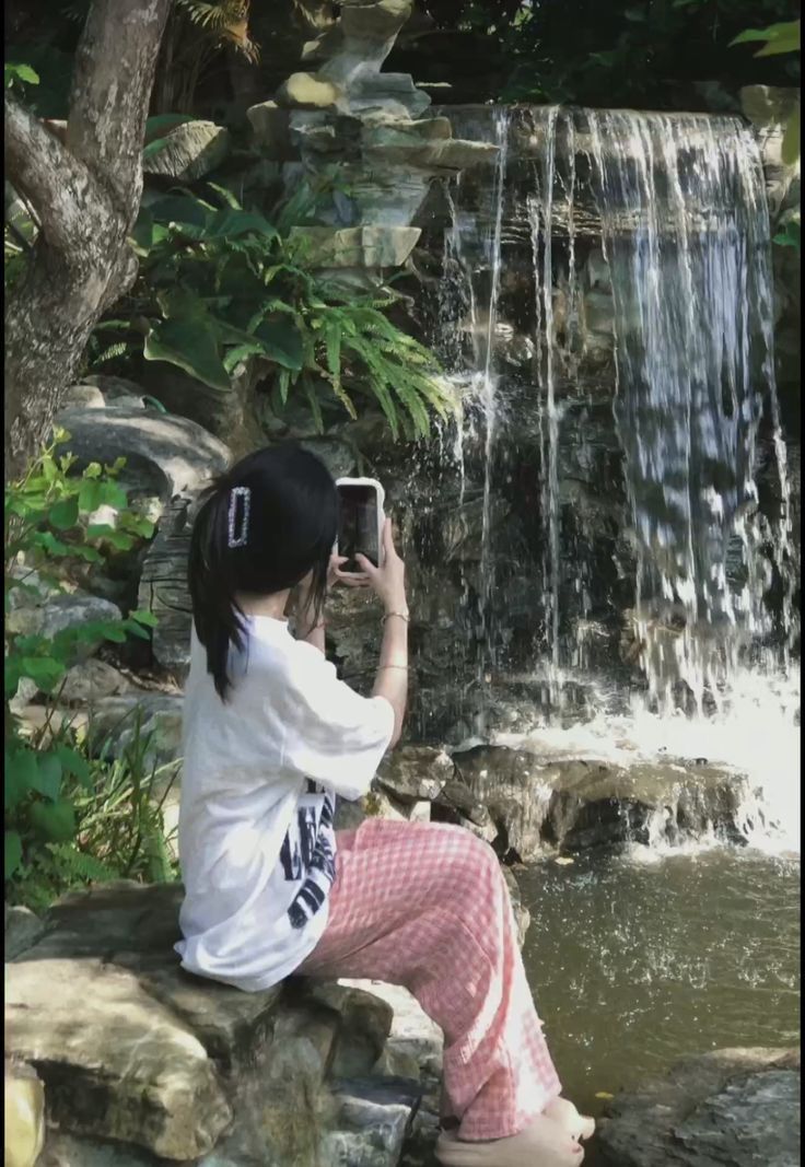 Cô gái trẻ mặc áo phông rộng và quần pijama bên dòng thác