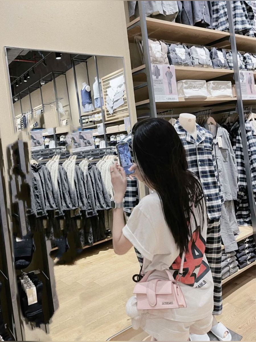 Cô gái trẻ mặc áo phông rộng và quần shorts chụp ảnh trước gương