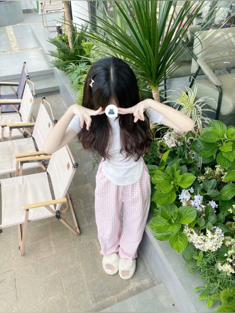 Cô gái trẻ mặc áo phông trắng và quần pijama kẻ sọc hồng