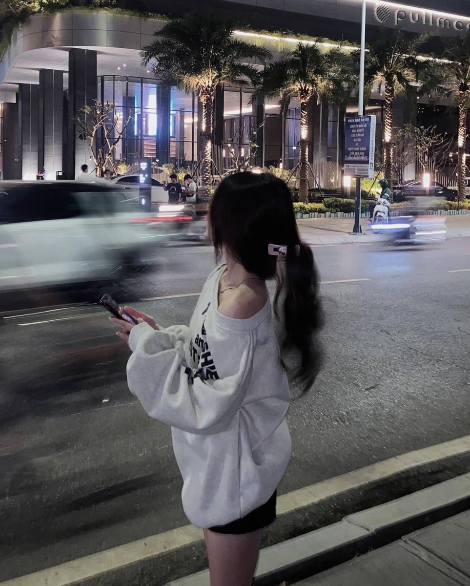 Cô gái trẻ mặc áo sweater oversized màu xám bên lề đường