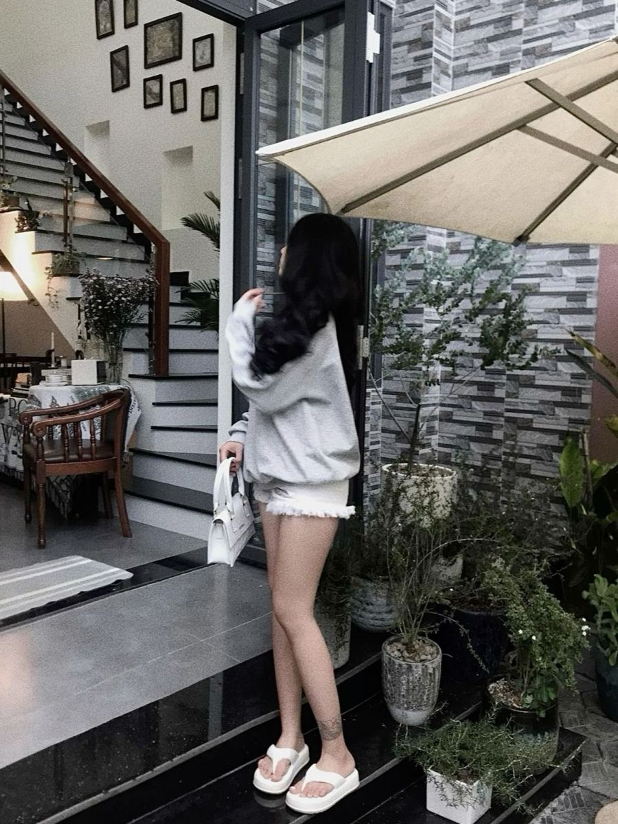 Cô gái trẻ mặc áo sweatshirt xám và quần short jeans