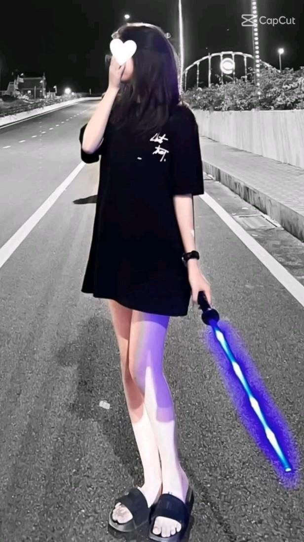 Cô gái trẻ mặc áo thun rộng màu đen giữa đêm vàng
