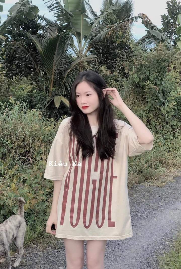 Cô gái trẻ mặc áo thun rồng với chữ 'VOGUE' giữa thiên nhiên xanh tươi