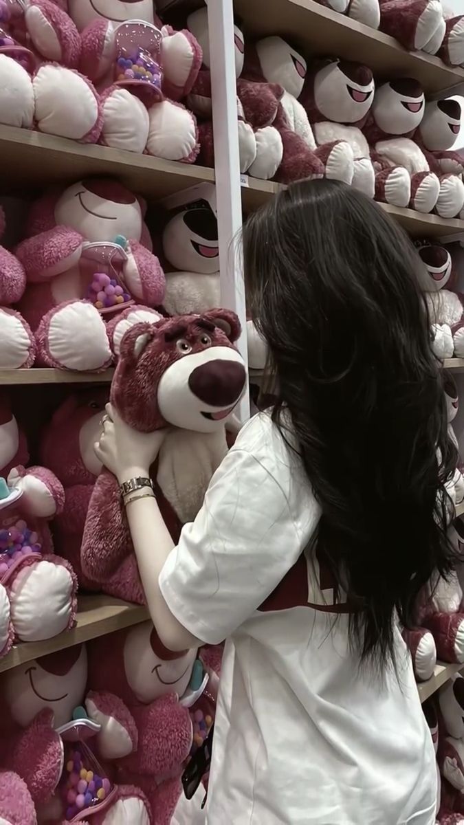 Cô gái trẻ mặc áo trắng ôm gấu bông giữa cửa hàng đồ chơi