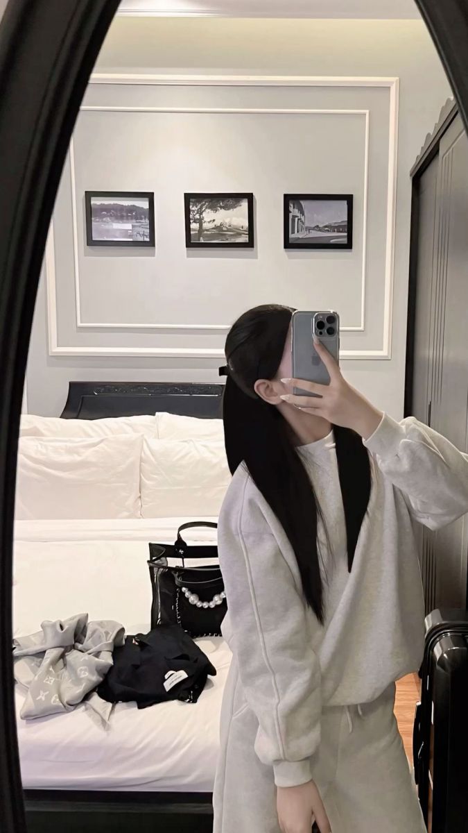 Cô gái trẻ mặc áo và quần thể thao màu xám chụp hình selfie trong gương