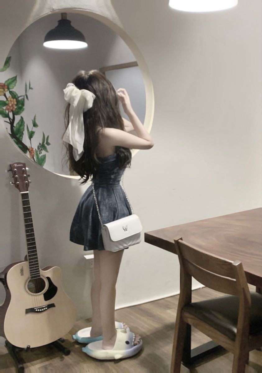 Cô gái trẻ mặc đầm ngắn xinh xắn trước gương
