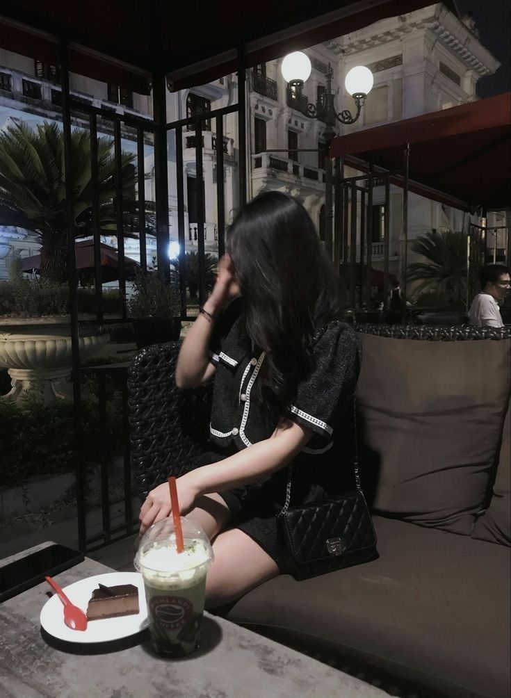 Cô gái trẻ mặc đồ tối màu thời thượng tại quán cà phê sang trọng
