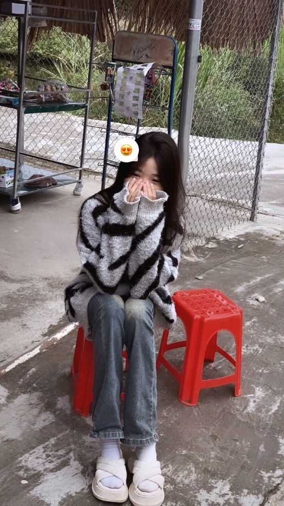 Cô gái trẻ mặc sweater sọc trắng đen và quần denim