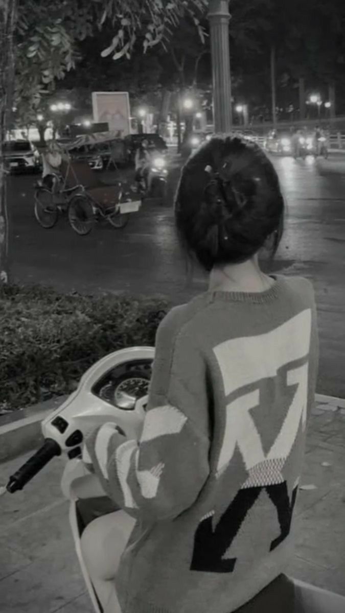 Cô gái trẻ mặc sweater xám ngồi trên xe máy tại phố Đồng Đức