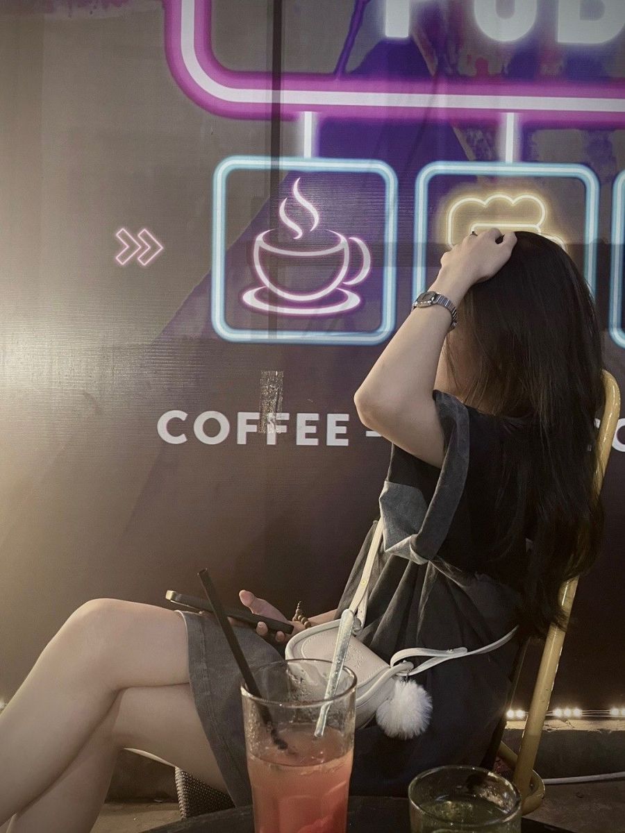 Cô gái trẻ mặc váy xinh đẹp khi ngồi ở quán cà phê