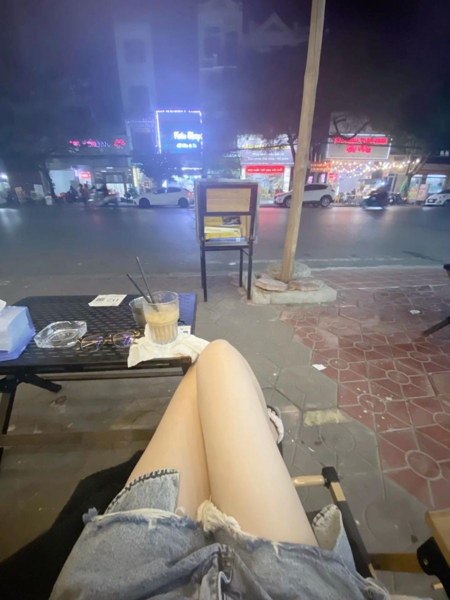 Cô gái trẻ ngồi trên ghế cafe, thưởng thức đồ uống thư giãn
