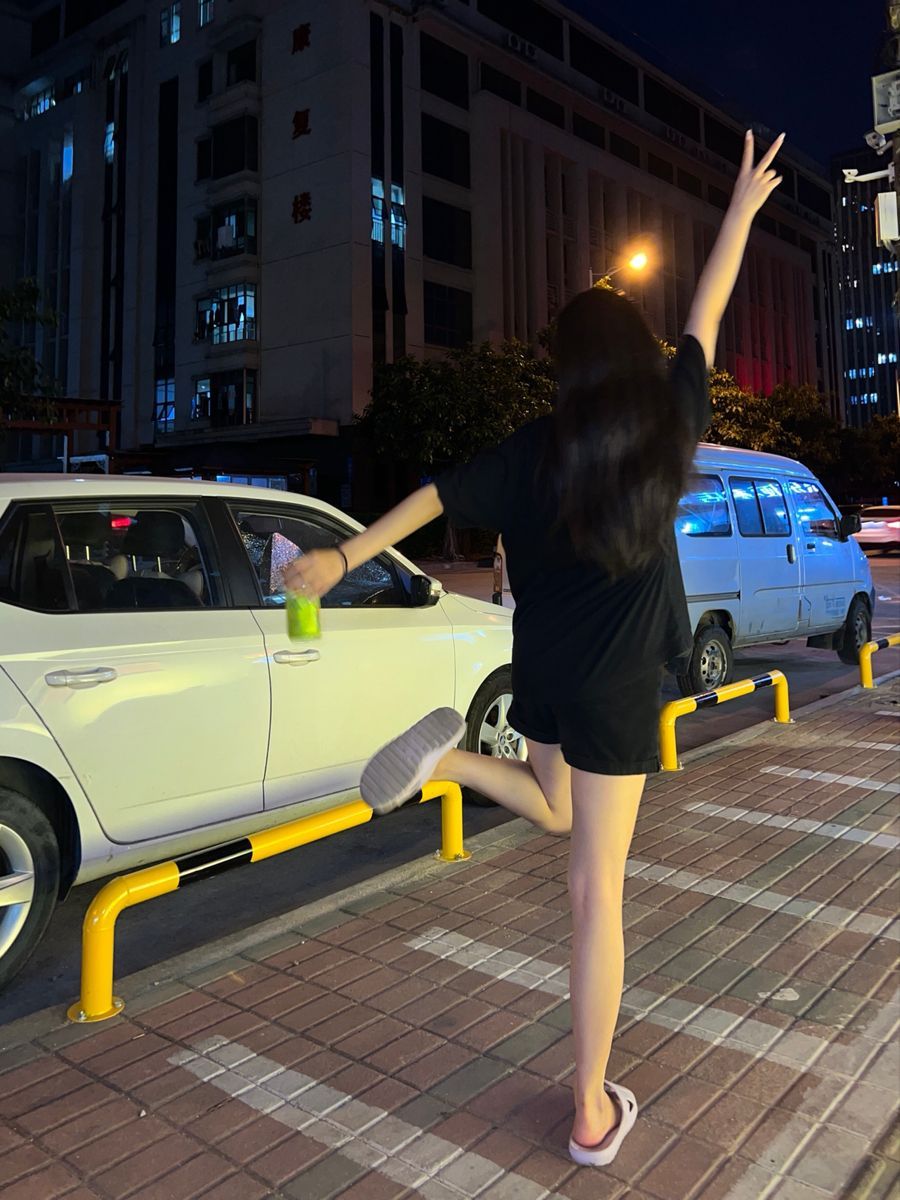 Cô gái trẻ trong áo phông đen và quần ngắn vui vẻ bên đường