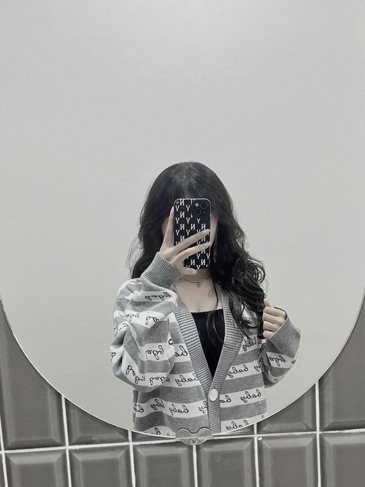 Cô gái trẻ với áo cardigan sọc xám chụp ảnh selfie trong gương