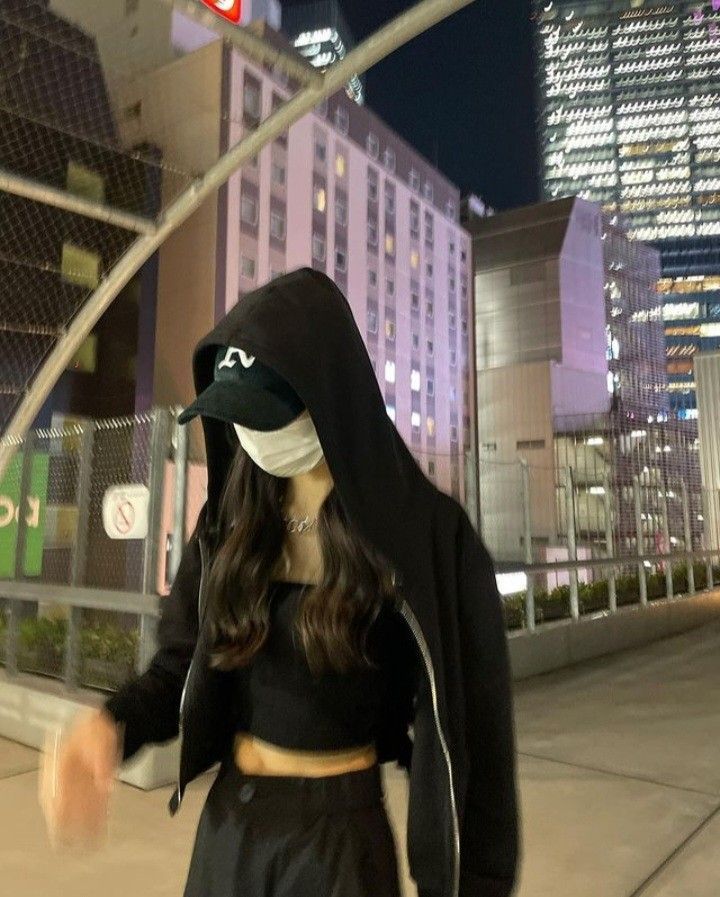Cô gái trẻ với áo hoodie đen và quần cạp cao dạo phố đêm