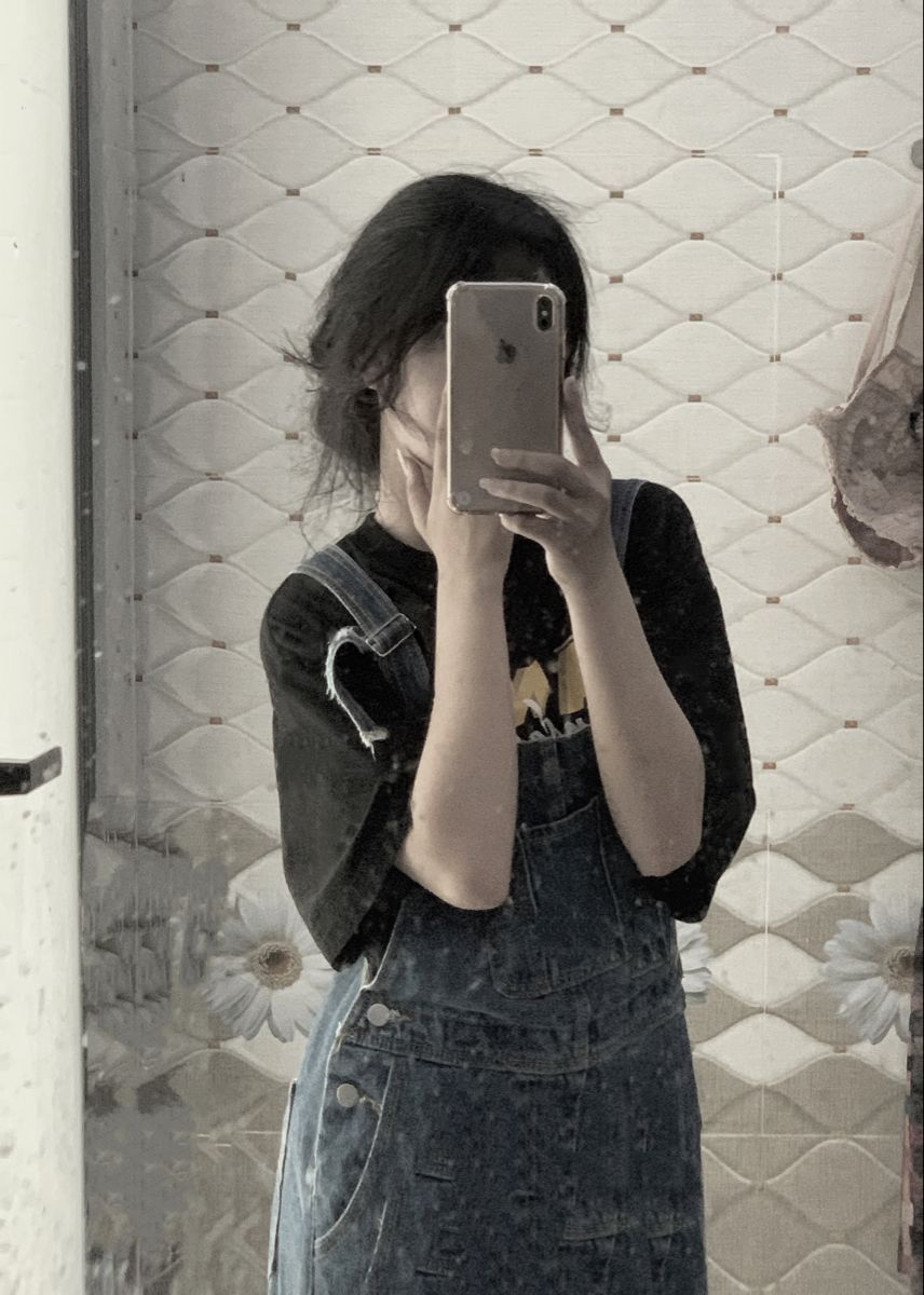 Cô gái trẻ với áo phông đen và quần yếm jeans