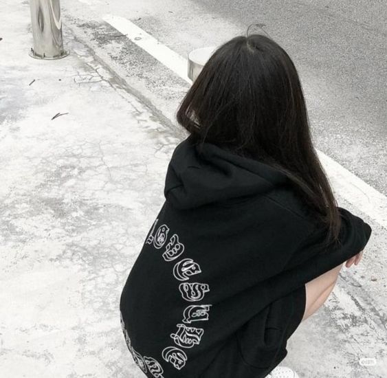 Cô gái trẻ xinh đẹp trong áo hoodie đen trên vỉa hè