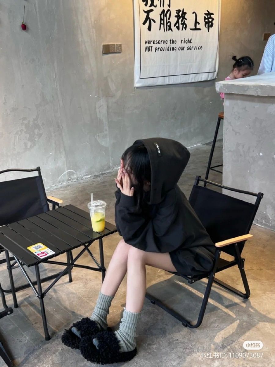 Cô gái trẻ xinh đẹp trong áo hoodie đen và quần ngắn sọc xanh