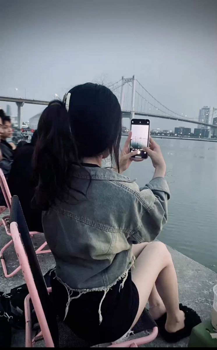 Cô gái xinh đẹp mặc áo khoác jean bên bờ sông