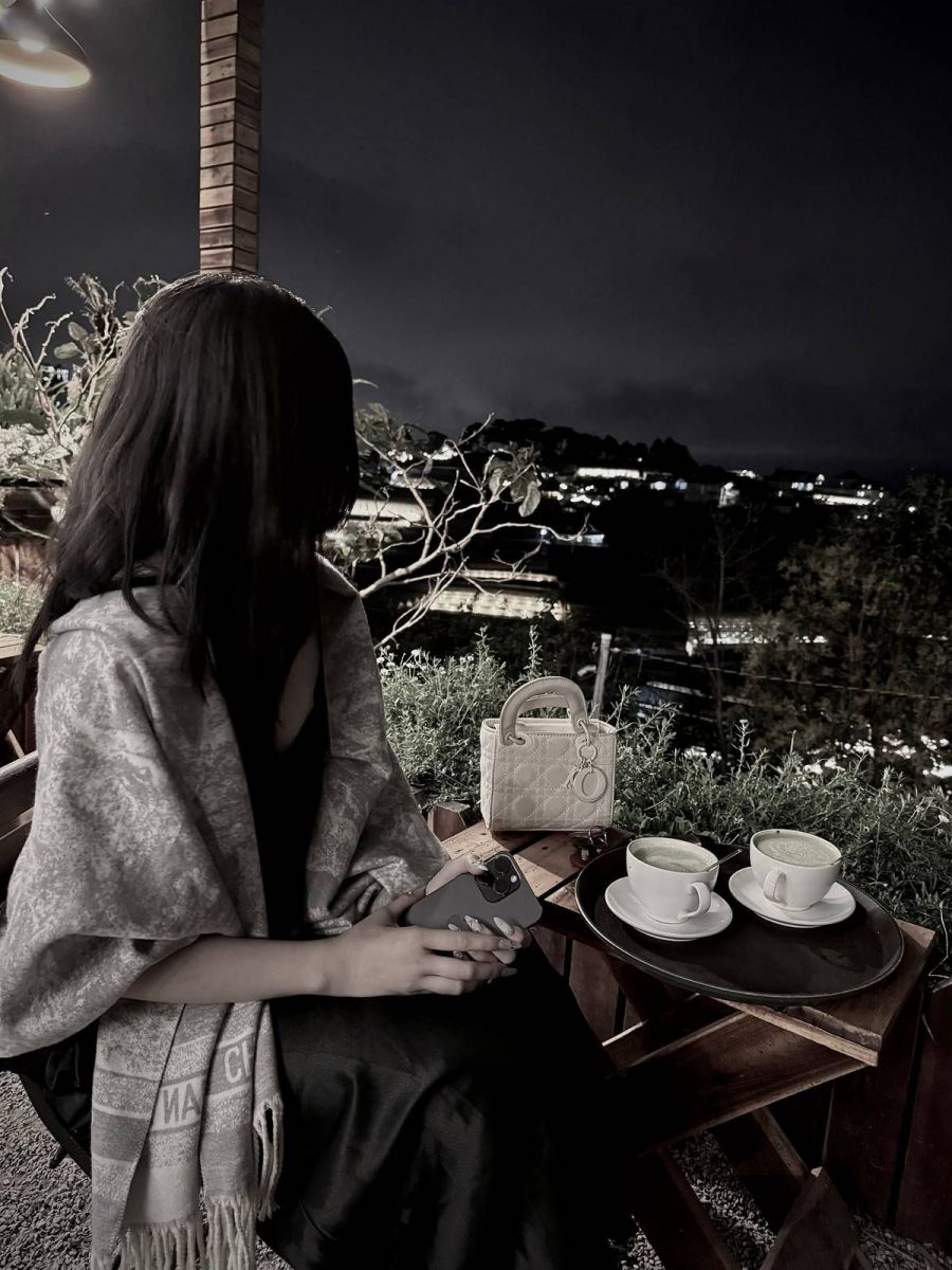Cô gái xinh đẹp ngồi ở quán cà phê vào ban đêm