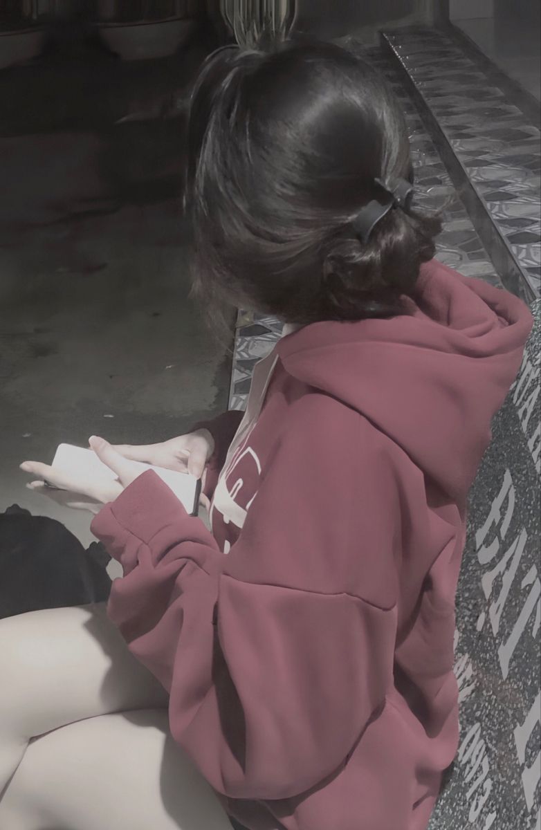 Cô gái xinh đẹp trong áo hoodie đỏ ngồi nghiêng trên ghế