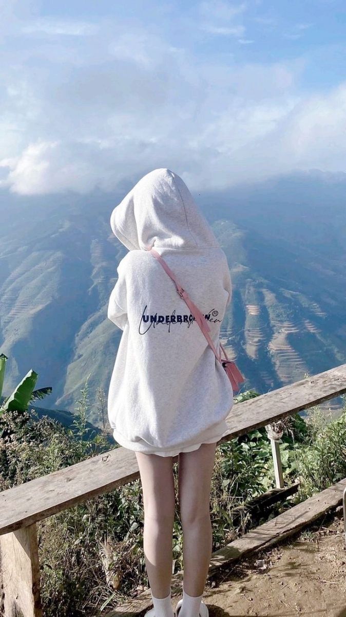 Cô gái xinh đẹp trong áo hoodie màu xám giữa rừng núi