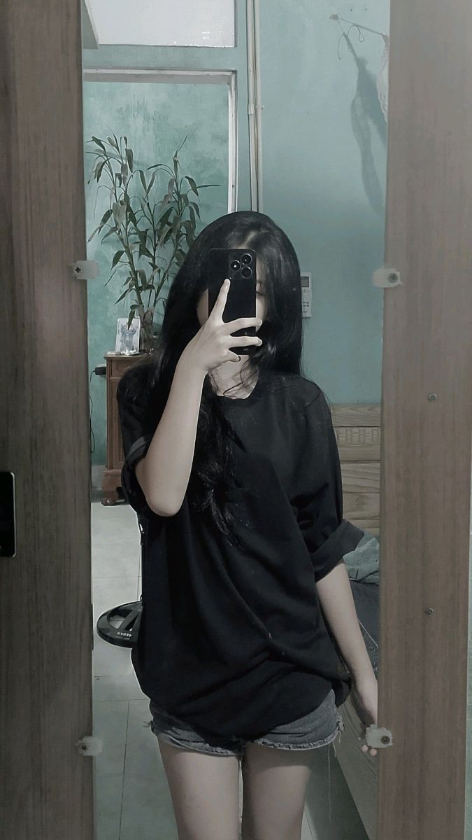 Cô gái xinh đẹp trong áo phông đen và quần short tạo dáng selfie