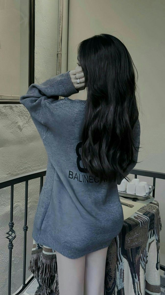 Cô gái xinh đẹp trong áo sweater màu xám bên cửa sổ