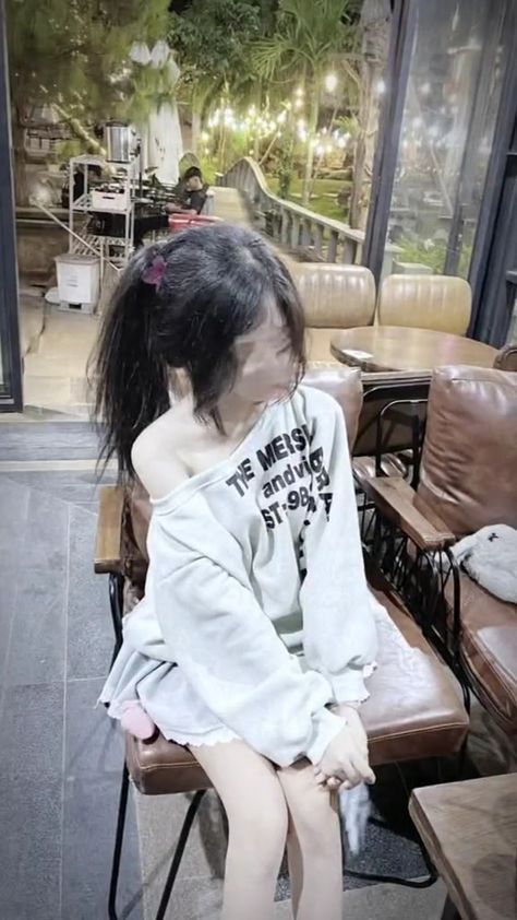 Cô gái xinh đẹp trong áo sweatshirt ngồi thư giãn tại quán cà phê