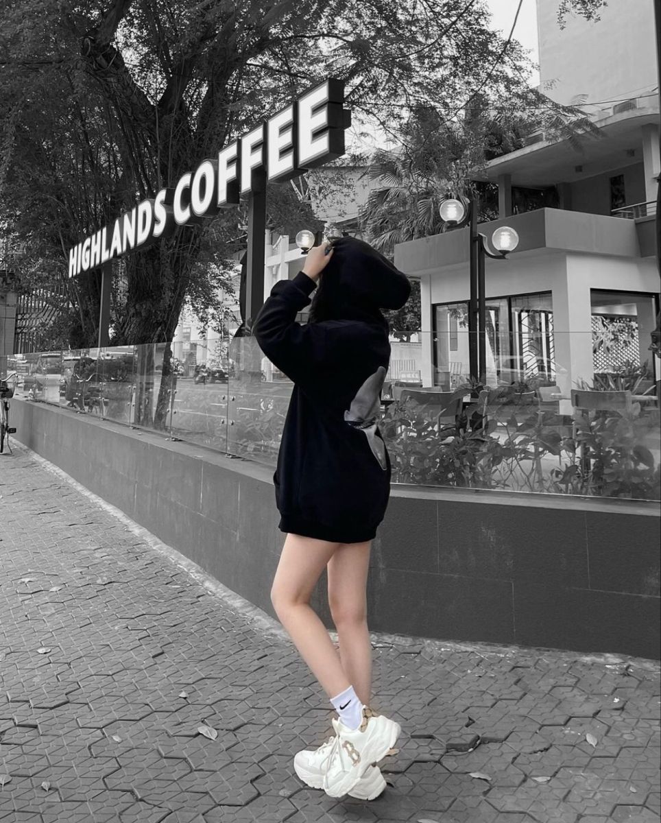 Cô gái xinh đẹp trong hoodie đen và giày thể thao trắng